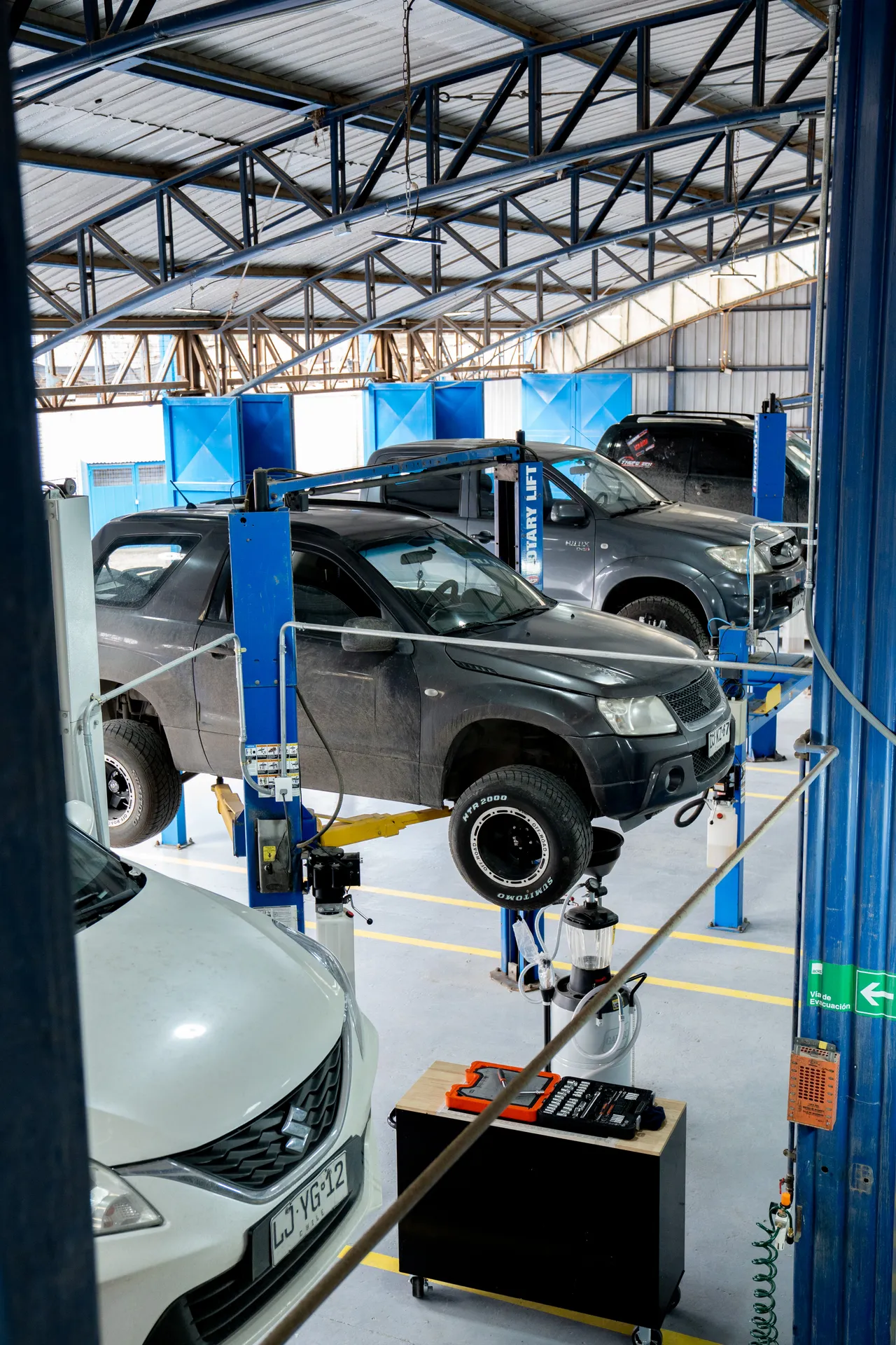 Camionetas en elevadores dentro del taller GESERMI, con carro de herramientas en primer plano